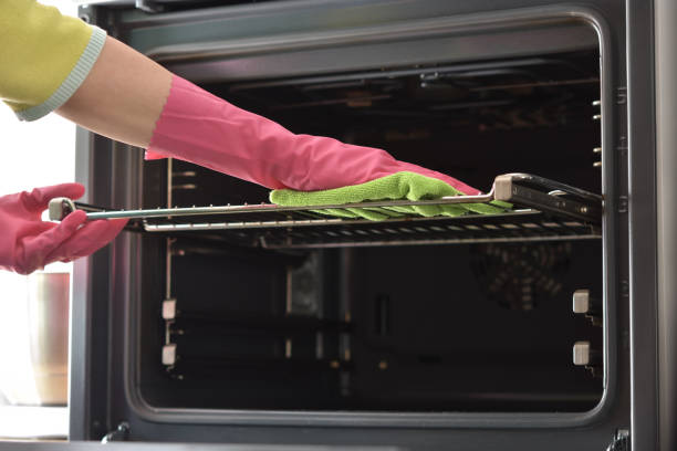 Close-up of person scrubbing oven racks with foil, showcasing cleaning power